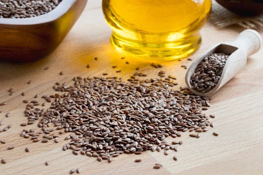 Flax seeds on a wooden table, with flax seed oil in the background