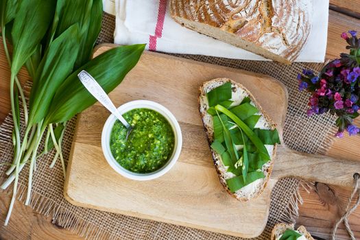 A slice of sourdough bread with butter and wild garlic, and homemade wild garlic pesto in a bowl