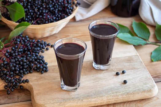 Two shots of black elder syrup with fresh elderberries