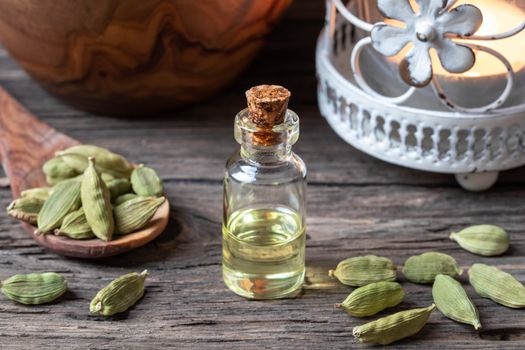 A bottle of essential oil with whole cardamon seeds