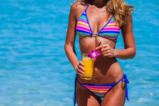 Woman in bikini with cocktail on beach in Thailand