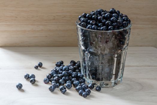 Blueberries in a glass with scattered berries. Good addition for your breakfast