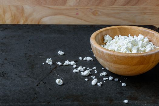 Bowl of cottage cheese for breakfast with scattered grains of curd. space for text