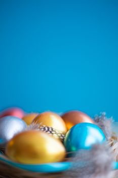 Beautiful Happy Easter holiday greeting banner with easter nest with colored eggs and decorated with ribbons over light wooden background with copy space for text on blue