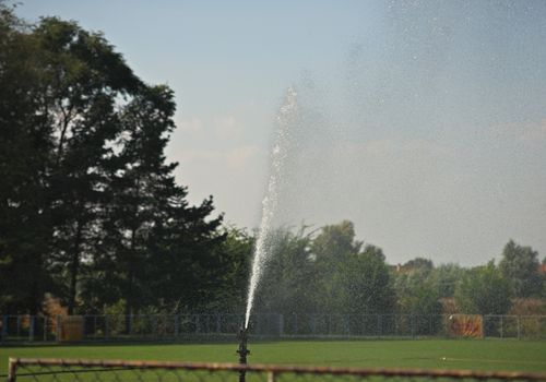 Sprinkler watering grass at football field