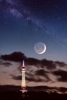 Petrin lookout tower (Petrinska rozhledna) in Prague, night landscape with new moon and fantastic starry sky and milky way, Czech Republic