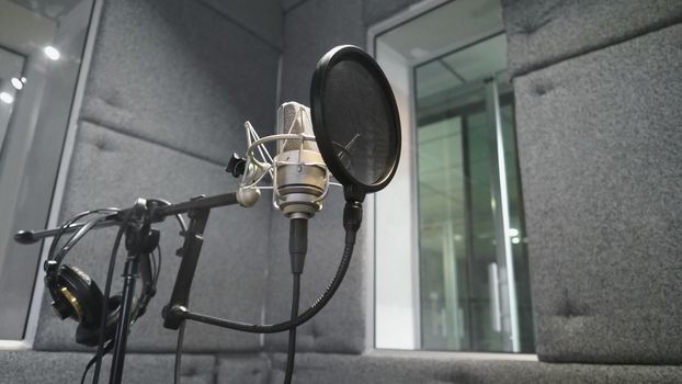 Studio microphone or mic for recording for vocal singer or commercial announcer with shock mount and pop filter on professional tripod in acoustic foam room for best sound and mix process