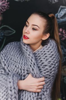 portrait of a beautiful young girl in a warm plaid on a black background