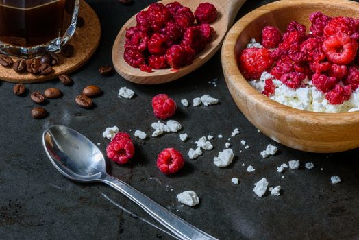 Cottage cheese with raspberries and coffee in a cup for breakfast with scattered berries, grains of curd and coffee beans