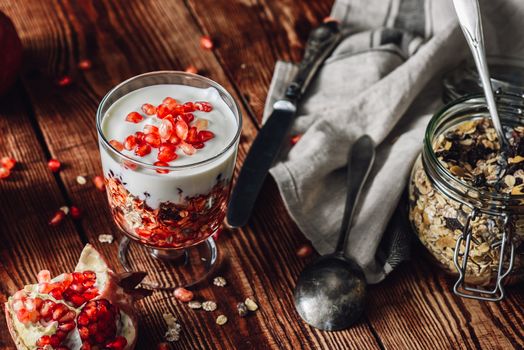 Prepared Dessert with Ingredients on Wooden Table. Series on Prepare Healthy Dessert with Pomegranate, Granola, Cream and Jam