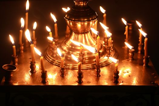 Christianity church interior. Set of lighting candles on dark background