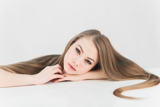 young girl woman with long blond hair lies on a white background