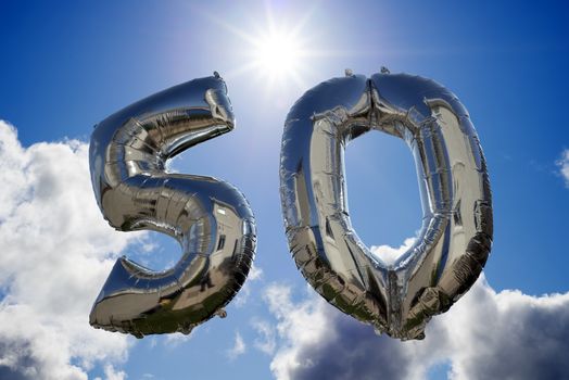 silver balloons for a 50th anniversary floating among the clouds