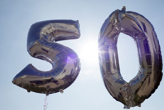 silver balloons for a 50th anniversary floating among the clouds