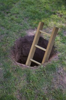 Ladder in deep dirt hole in ground or lawn