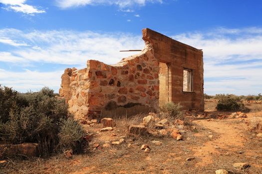 Desolated old stone home fallen into ruin and crumbling in a dry arid desert place in Central Australia