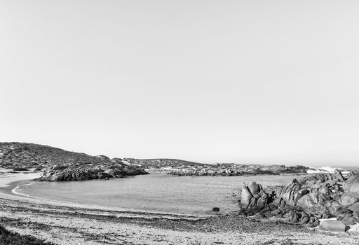 A view of Tietiesbaai Caravan Park in the Cape Columbine Nature Reserve near Paternoster. An ablution building and a motorhome are visible. Monochrome