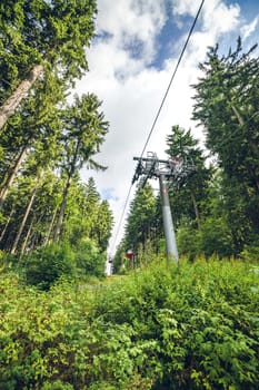 Mountain lift on a green forest with tall pine trees in the summer
