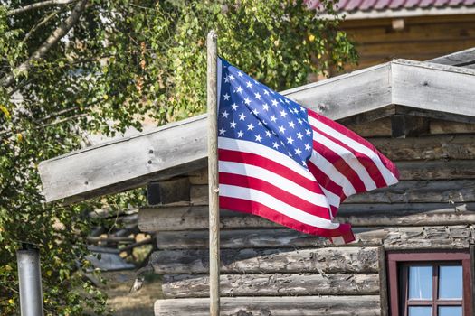 The flag of USA outside a wooden cabin in the wild west