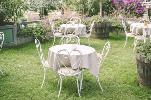 Romantic garden setting with vintage furniture and table cloth surrounded by flowers