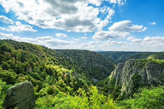 Large creek from above with forest and cliffs under a bright blue sky