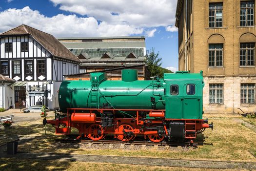 Green and red locomotive on tracks at a train station