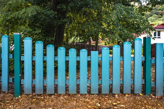 Blue fence gate  at a yard in the fall with trees in the background