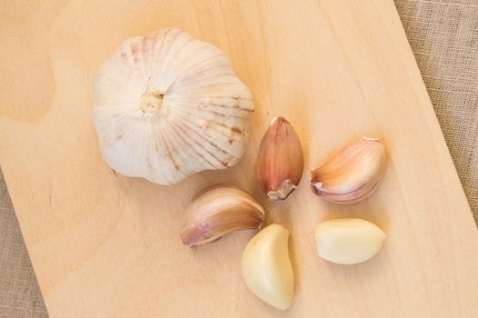 Cloves and clove of garlic on wooden cutting Board.