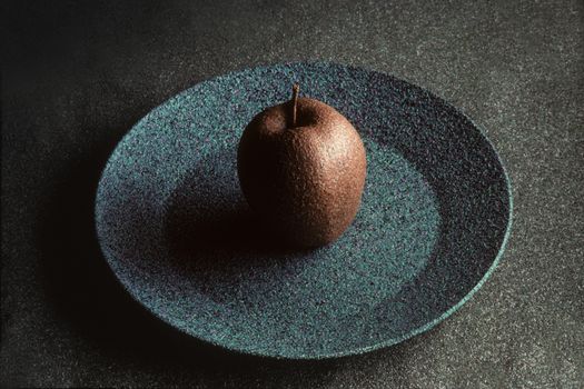 Granite-like sculpture of an apple on a plate