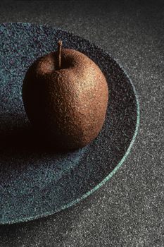 Granite-like sculpture of an apple on a plate