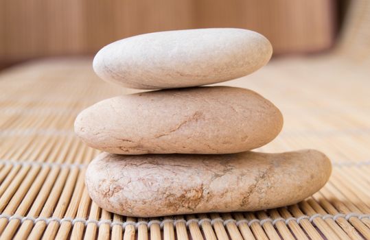 Stones stacked in a pyramid for meditation, background bamboo Mat.