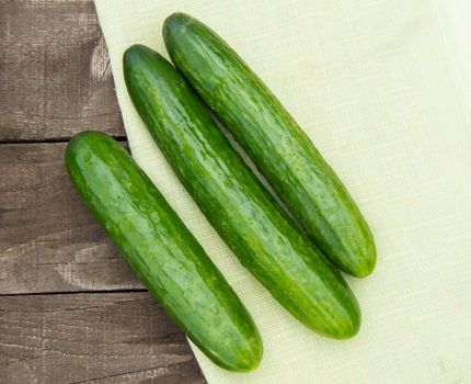 Cucumbers are lying on an old wooden background with napkin.