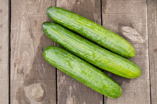 Fresh cucumbers on old wooden background, top view.