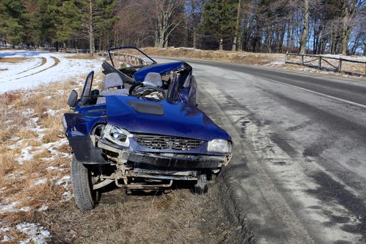 Front of blue car damaged by crash accident on side of the road