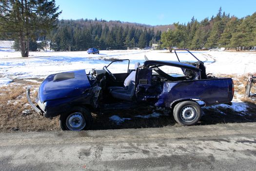 Blue car damaged by crash accident on side of the road