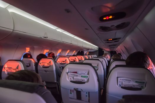 Inside flying passenger aircraft during sunrise with red light shining in