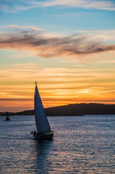 Orange and yellow sky above harbor port coast sunset sailing boat
