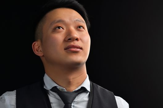Portrait of an Asian young man looking up, dressed in a shirt, smiling