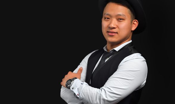 A cute Asian man looking into the camera and smiling, standing on a black background, a horizontal photo