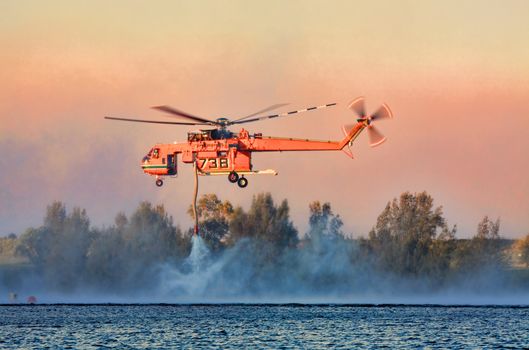 Penrith, Australia - October 23, 2013:  NSW Rural Fire Service using the Sikorsky Erickson Air-Crane to fight  large bush fires and protect property in difficult terrain in the Blue Mountains.  Dense heavy smoke fills the air. 