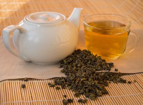 Teapot and Cup of herbal green tea on bamboo napkin.