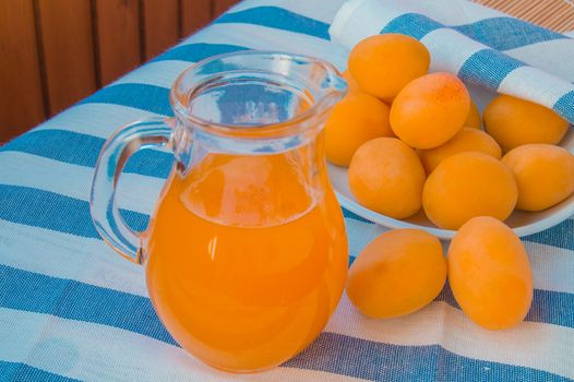 Fresh apricot juice in a glass jar, apricots on striped napkin.