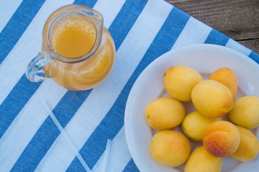 apricot juice in a Glass jug with straw and fruit on napkin