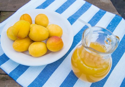 apricot juice in a Glass jug with straw and fruit on napkin.