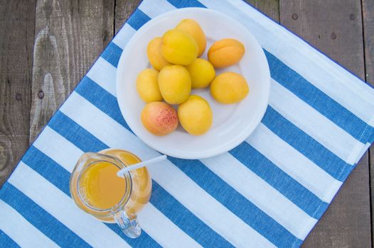 apricot juice in a Glass jug with straw and fruit on napkin