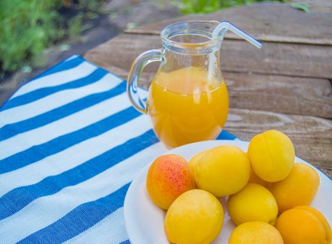 apricot juice in a Glass jug with straw and fruit on napkin.