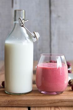 Goats milk kefir with strawberries on a wooden background