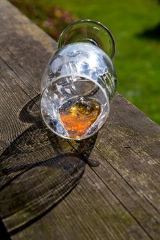 Overturned glass of beer on wooden table. Beer is an alcoholic drink made from yeast-fermented malt flavoured with hops. Overturned beer glass. 


