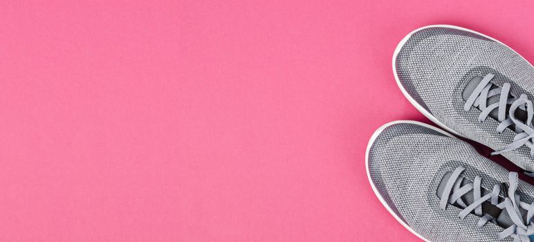 Grey sneakers on pink background. Flat lay, top view minimal background. Fashion blog or magazine concept.