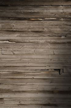 Exterior weathered wooden wall with unpainted planks, lit diagonally